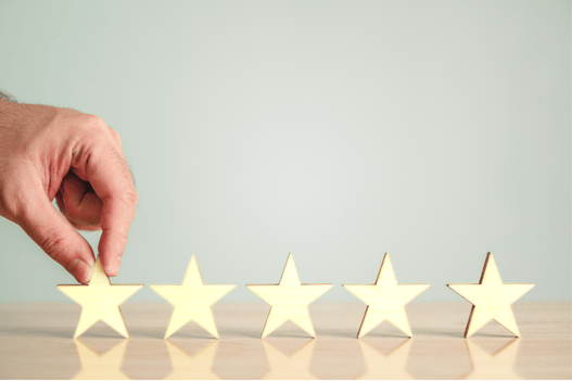 A man's hand holds one of 5 stars on a table, indicating his satisfaction with his Trane's performance and service. 