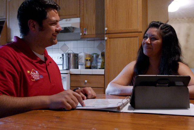 An A&E salesman walks a buyer through the documents of their newest HVAC purchase.