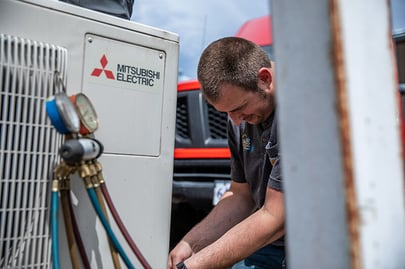 An A&E HVAC technician works on a Mitsubishi Electric HVAC unit.