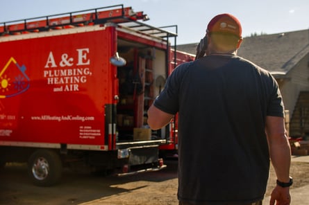 An A&E plumber walks back to an A&E work van after a successful job completed.