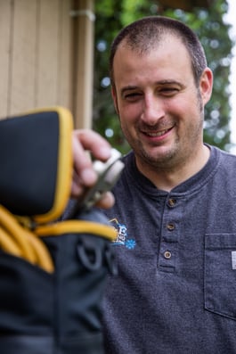 An A&E Plumbing, Heating and Air HVAC technician works on HVAC equipment outdoors.