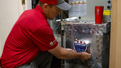 An A&E Plumbing, Heating and Air HVAC tech performs work on an HVAC unit.