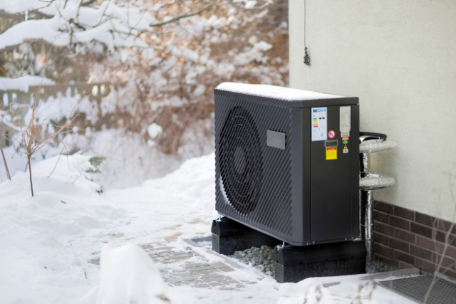 Outdoor Mitsubishi unit sits on a concrete pad in the middle of winter.