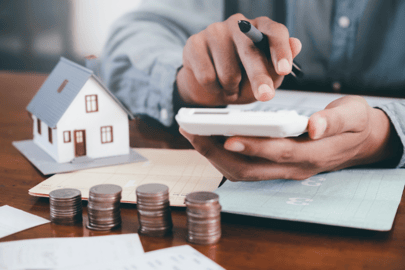 A man sits with a calculator and money, figuring out his finances to afford his new HVAC unit.