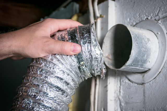 A person works with flexible indoor HVAC duct work.