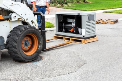 A forklift brings a residential generator up to the house to be installed.