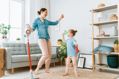 Mom and daughter dancing in a temperature-regulated room while doing chores, a clear indication that their HVAC is running smoothly.