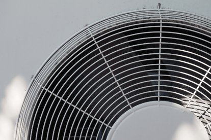 A close-up of an HVAC fan blade behind the circular vent cover.