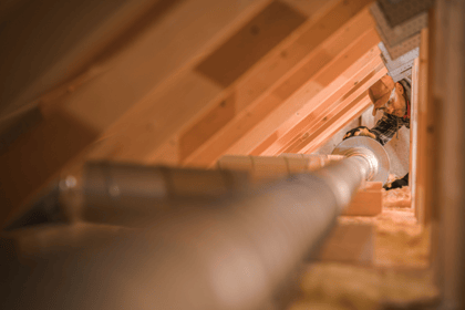 An HVAC technician works on a residential duct work system.