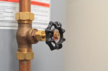 A black water valve for a residential home's water protrudes from the house's water meter. 