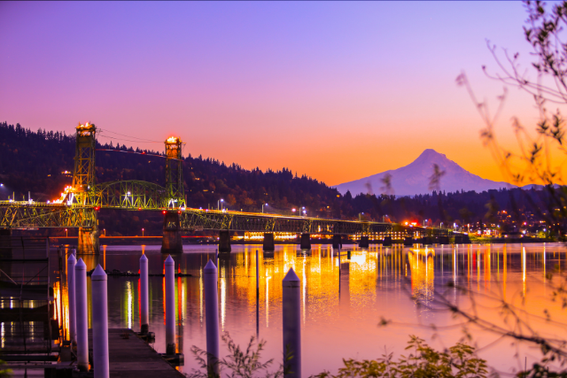 The Hood River Bridge spans across the foreground of the shot, Mt Hood in the background as the sun sets.