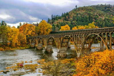 An Oregon bridge is surrounded with Fall foliage. 