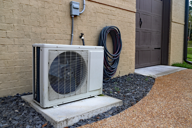 The outdoor component to an HVAC mini split system sits on a concrete slab outside of the home.