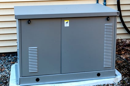 Residential whole-home generator on a concrete slab outdoors.