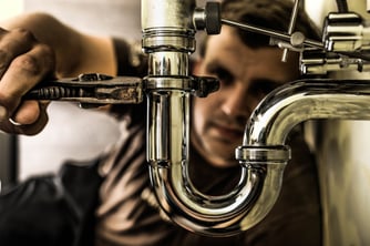 A plumber expertly works on a home's indoor plumbing fixtures.