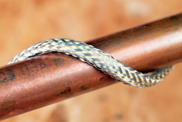 A closeup shot of a heat cable wrapped around a home plumbing copper pipe.