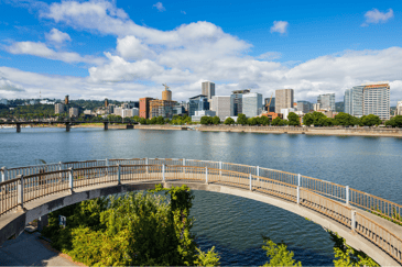 A bridge stretches over the Willamette River, a view of Portland beyond the waters.