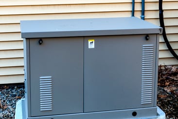 A small whole-home generator outdoors on a concrete pad.