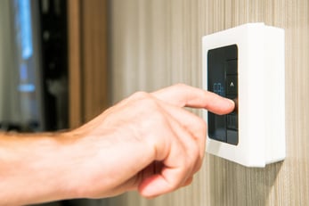 A person reaches over to adjust their home's temperature on a smart thermostat.