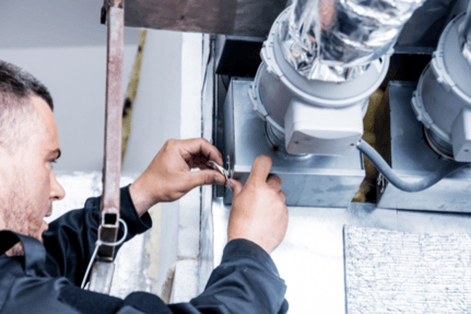 An HVAC technician works to repair a commercial ductwork system.