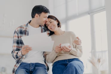 A man gives a side embrace to a woman as they look over their HVAC warranty, smiling in relief at their safety net.