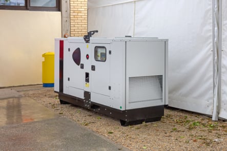 An outdoor whole-house generator has just been installed, protective equipment still around it.