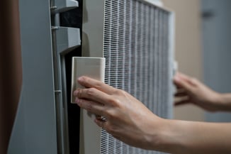 A woman's hand removes the HEPA air filter in her HVAC system.