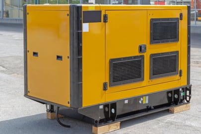 A big yellow residential generator sits on an outdoor concrete setting.